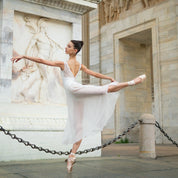 Arabesque in a white leotard under Arco della Pace