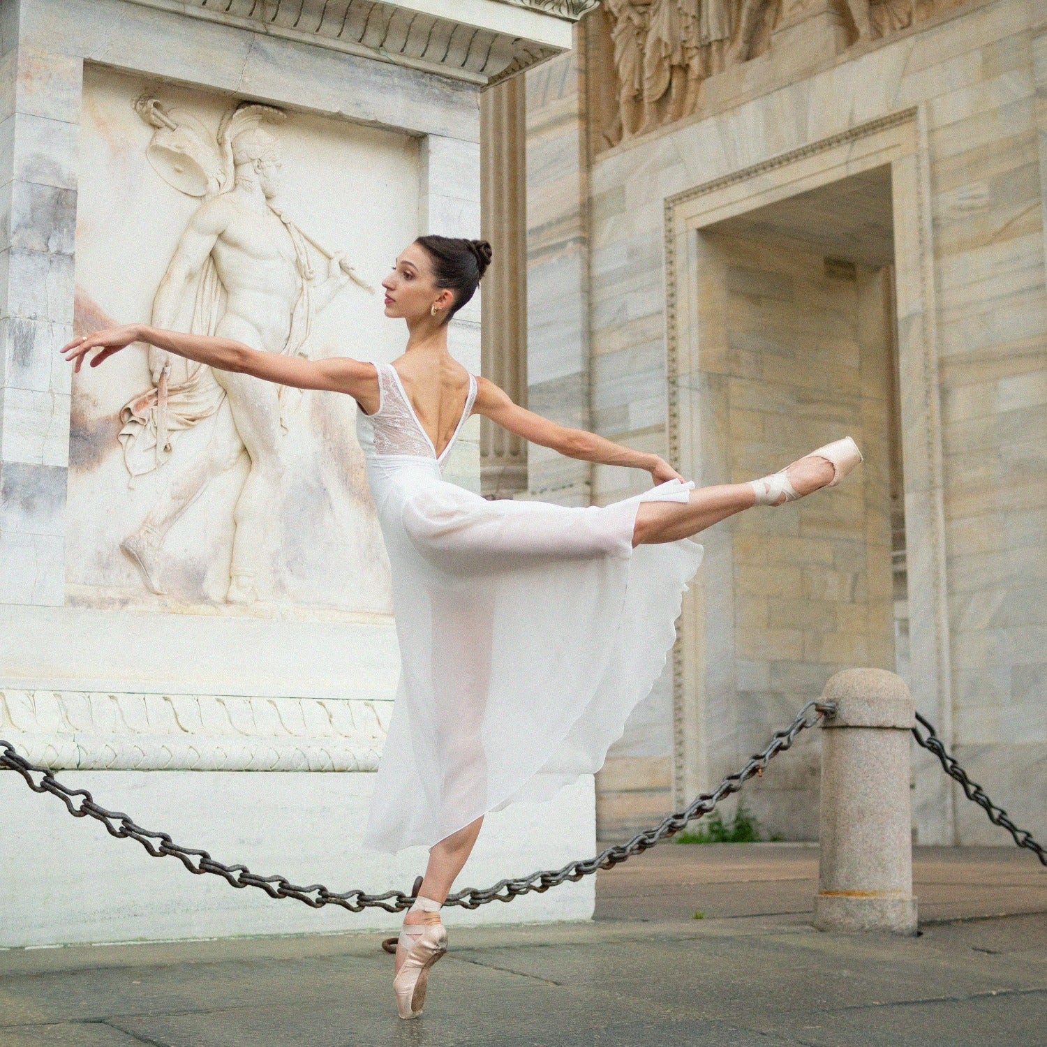 Arabesque in a white leotard under Arco della Pace