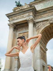 a dancer is dancing with a white leotard under the Arco della Pace in Milan